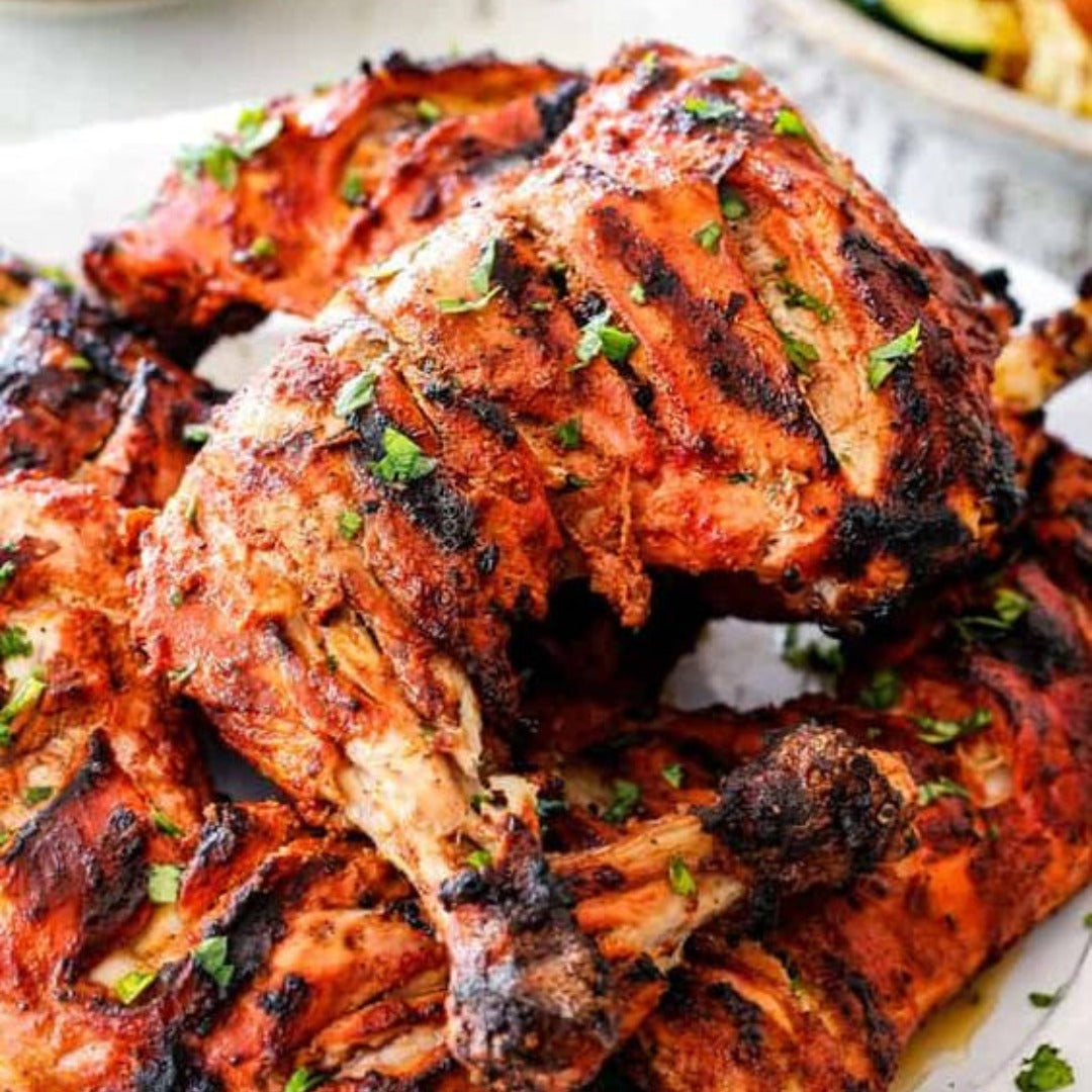 Tekka chicken features juicy, marinated legs and thighs with char marks and fresh herbs. The well-seasoned, reddish pieces come ready to cook—perfect for an easy meal inspired by classic tikka flavors.