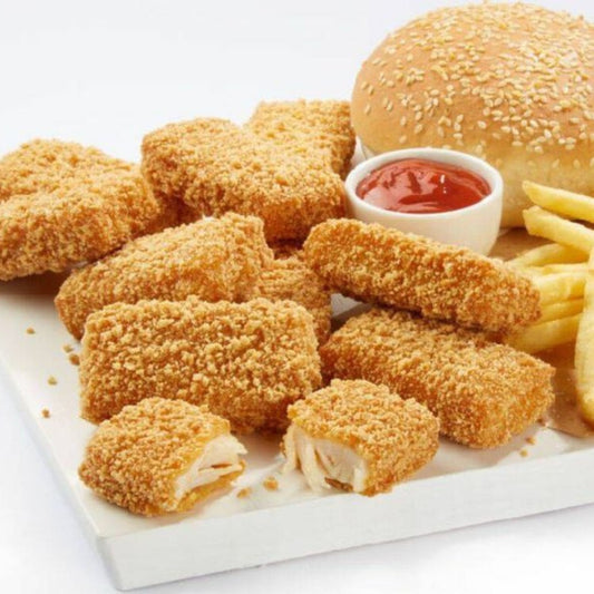 A white tray with Mesahab—breaded chicken nuggets made from whole chicken pieces, a sesame seed bun burger, golden French fries, and a small cup of ketchup. One nugget is cut open to reveal the white meat inside.