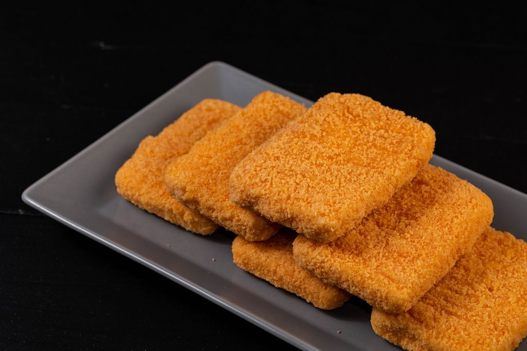 Five rectangular, golden-brown Roumy Cubes with crispy breading are neatly arranged on a gray plate against a black background, creating an irresistible bite-sized appetizer.
