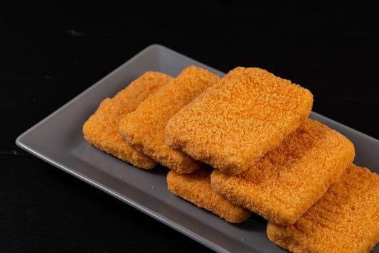 Five rectangular, golden-brown Roumy Cubes with crispy breading are neatly arranged on a gray plate against a black background, creating an irresistible bite-sized appetizer.